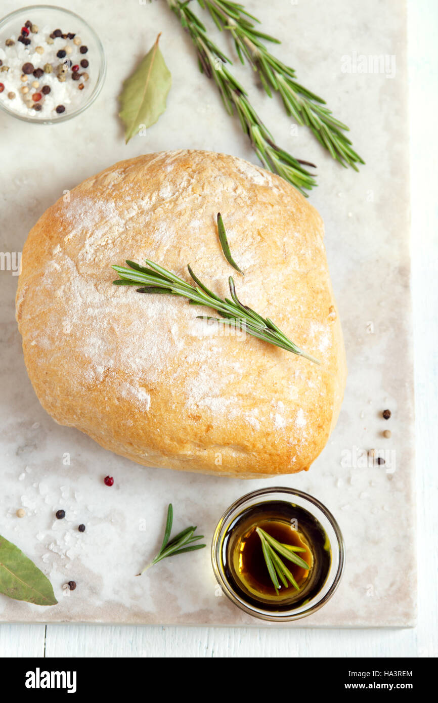 Fresh ciabatta bread with rosemary and extra virgin olive oil on rustic white background Stock Photo