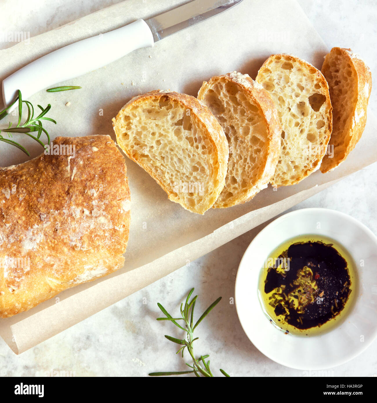 Italian bread Ciabatta with olive oil and rosemary on white marble background - fresh homemade bread bakery Stock Photo