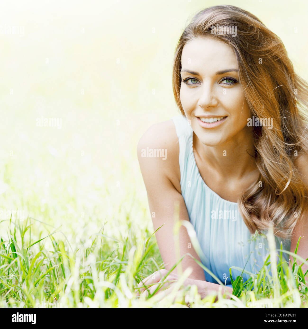 beautiful young woman in blue dress lying on grass Stock Photo - Alamy
