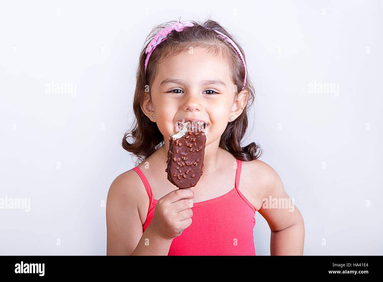 Young girl feeling happy while eating chocolate ice cream bar Stock
