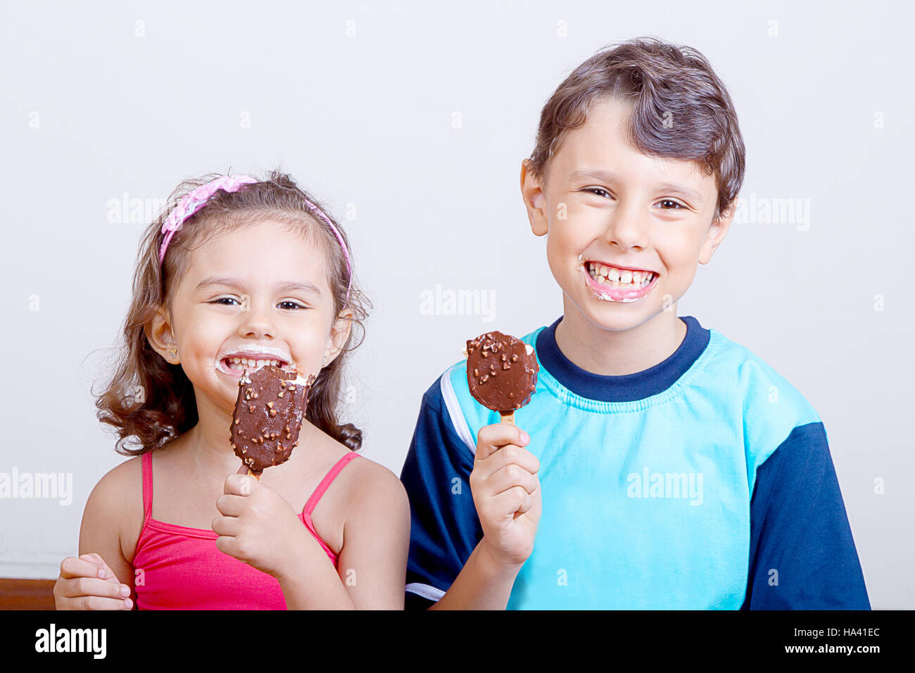 Young boy and girl feeling happy while eating chocolate ice cream bar Stock Photo