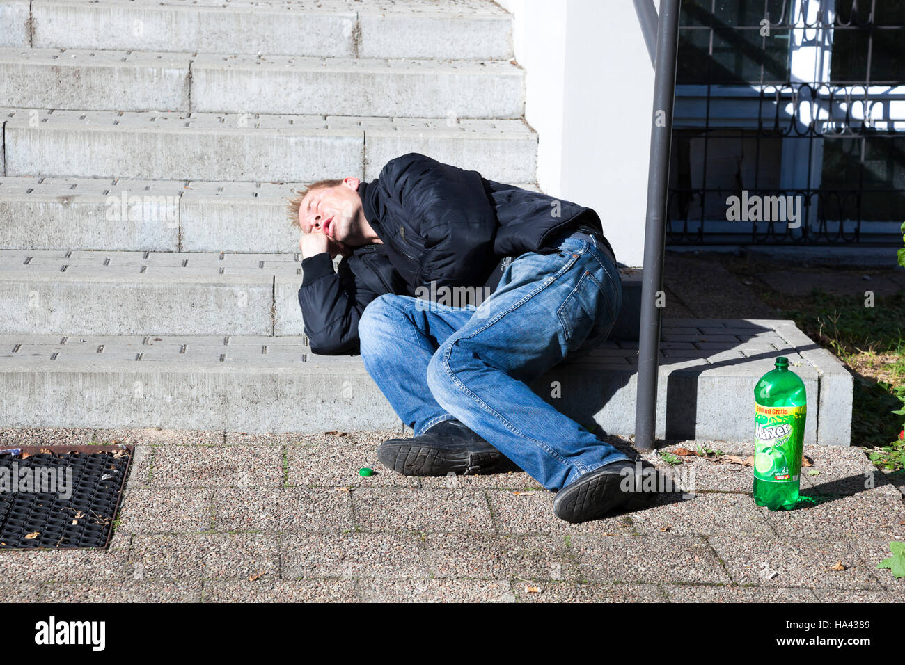 Drunkard sleeping on public stairs in the street Stock Photo