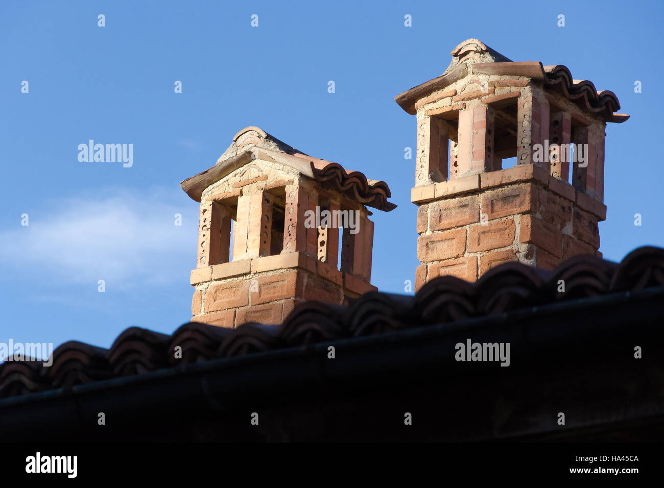 Two brick chimneys on tile roof against clear blue sky Stock Photo - Alamy