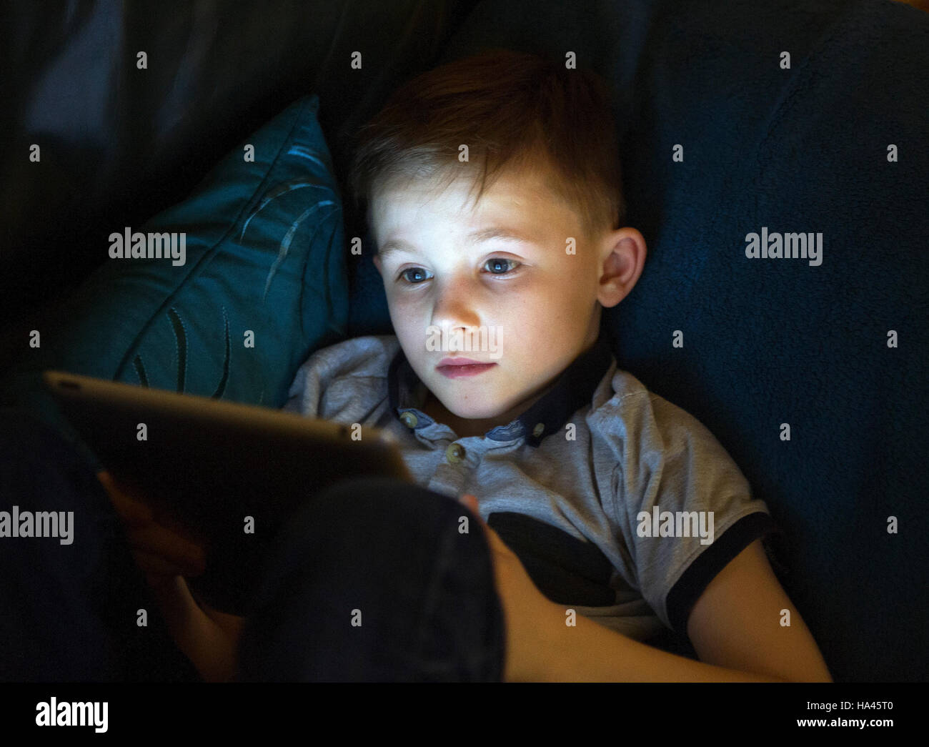 Young boy sitting using Apple ipad to access the internet using wireless technology. Stock Photo