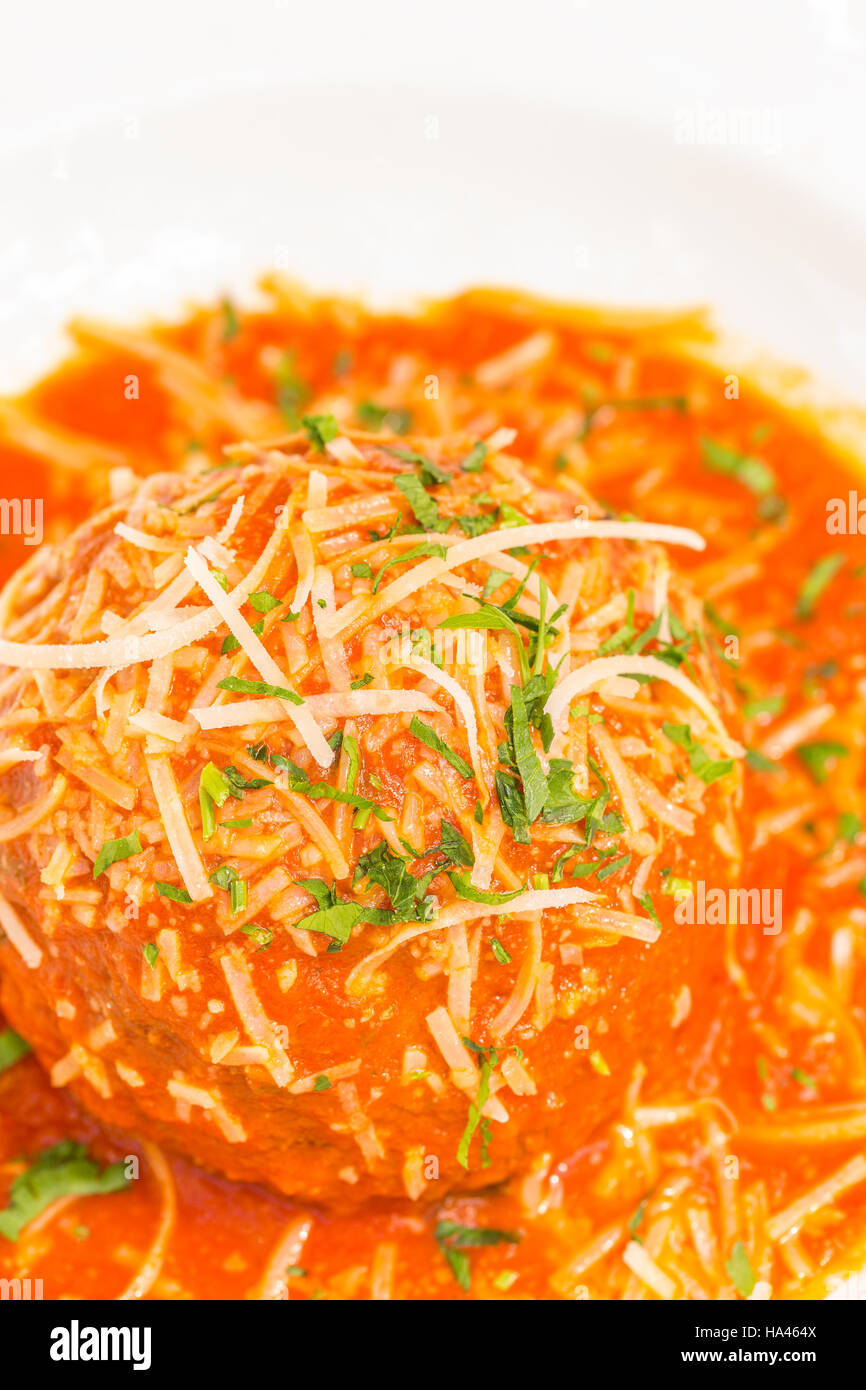 A very large Italian meatball bathed in rich pomodoro sauce, garnished