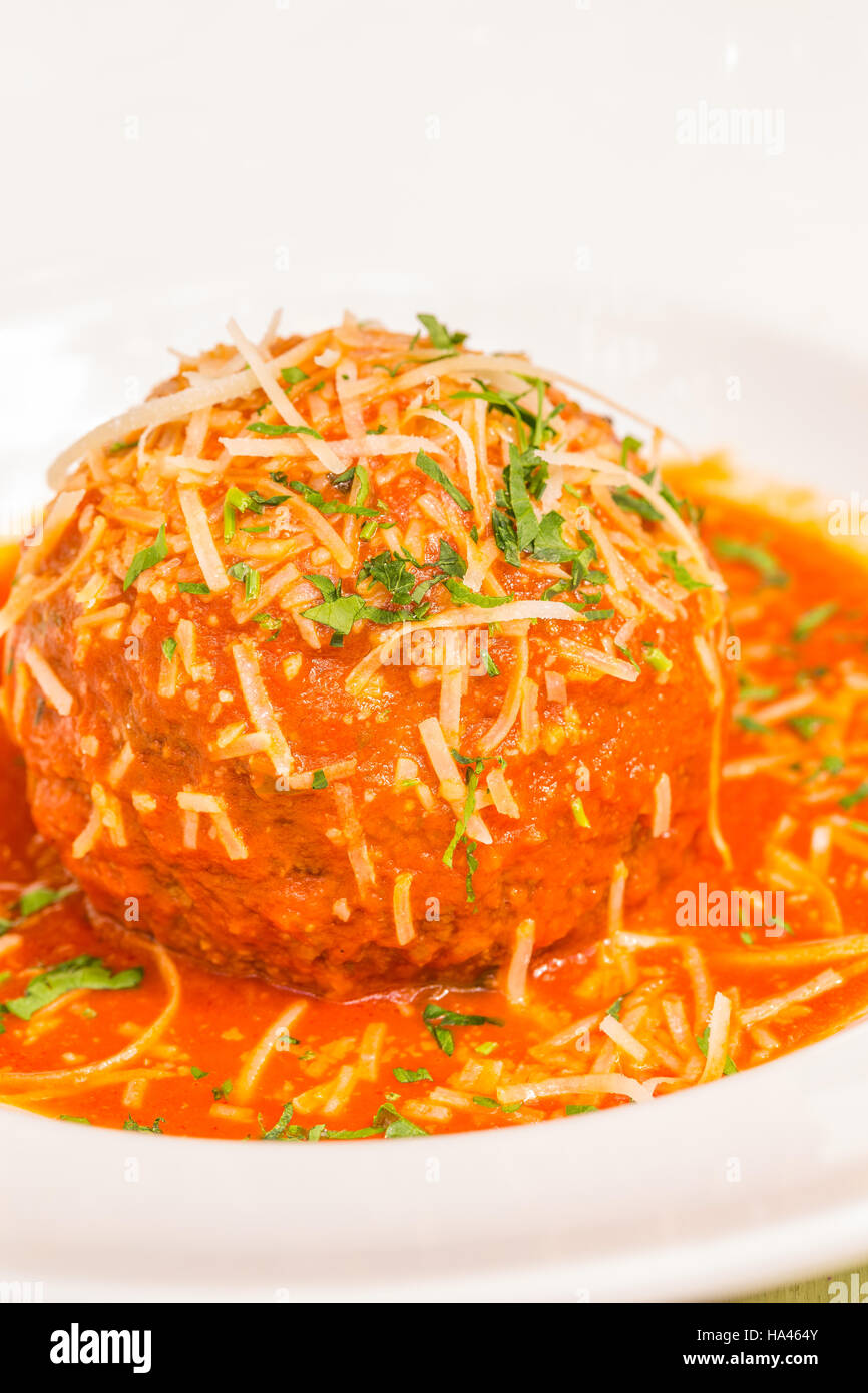 A very large Italian meatball bathed in rich pomodoro sauce, garnished