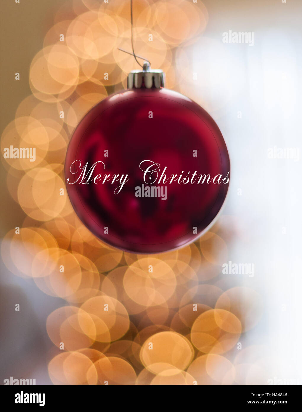 Single Red Happy Holidays Ornament hanging in front of lights Stock Photo