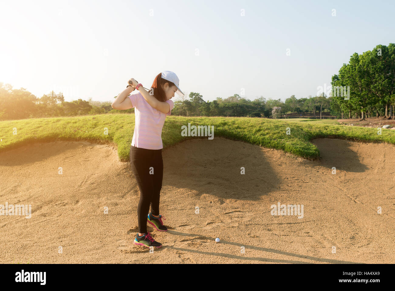 Asian woman golf player hitting golf ball out of sand trap. Golf sport concept. Stock Photo