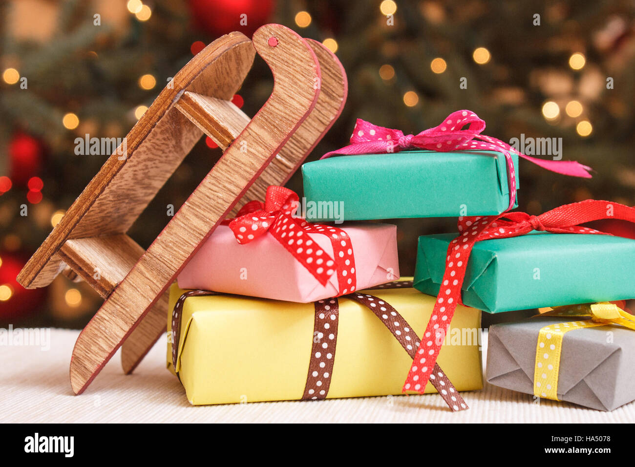 Colorful wrapped gifts with ribbons for xmas, wooden sled and christmas ...