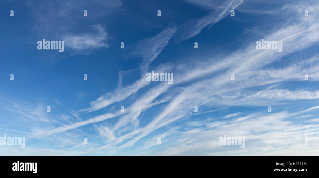 A blue sky heavily marked by aircraft vapour trails Stock Photo
