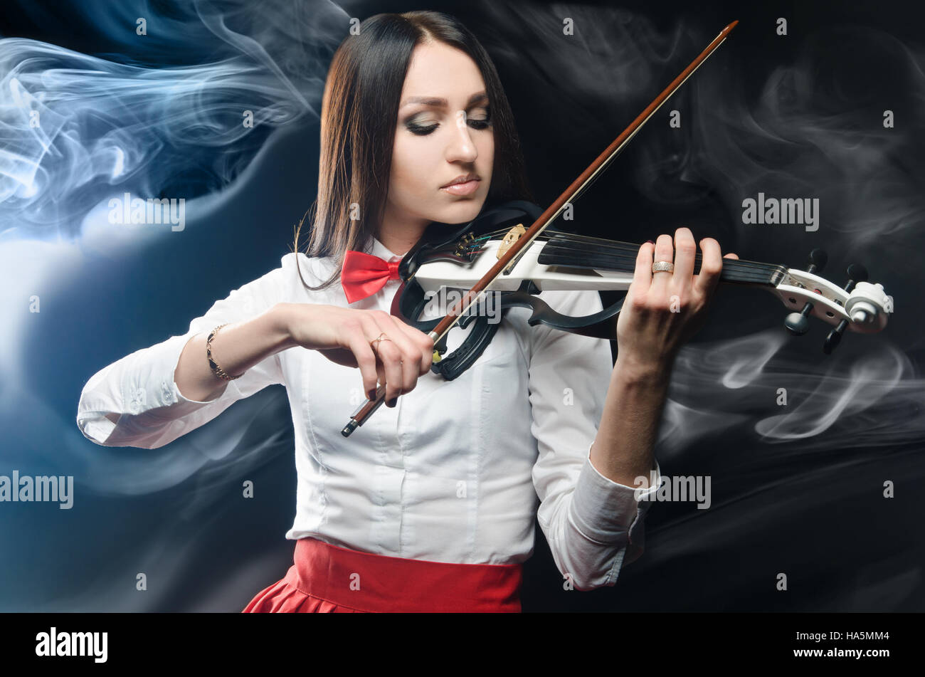 Dreamy woman playing the violin on a black background Stock Photo - Alamy