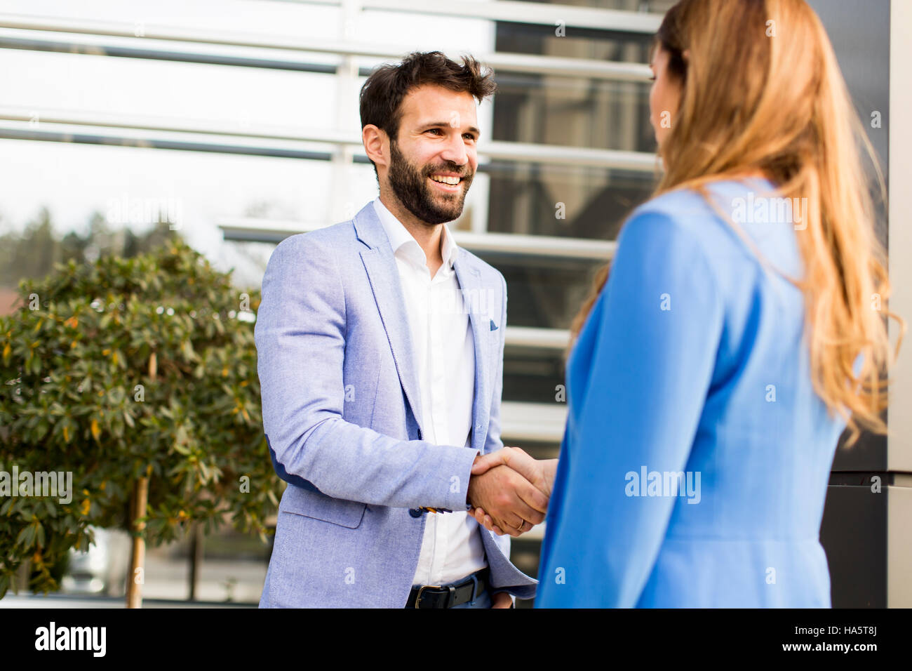 Young business people shake hands in front of the office building Stock