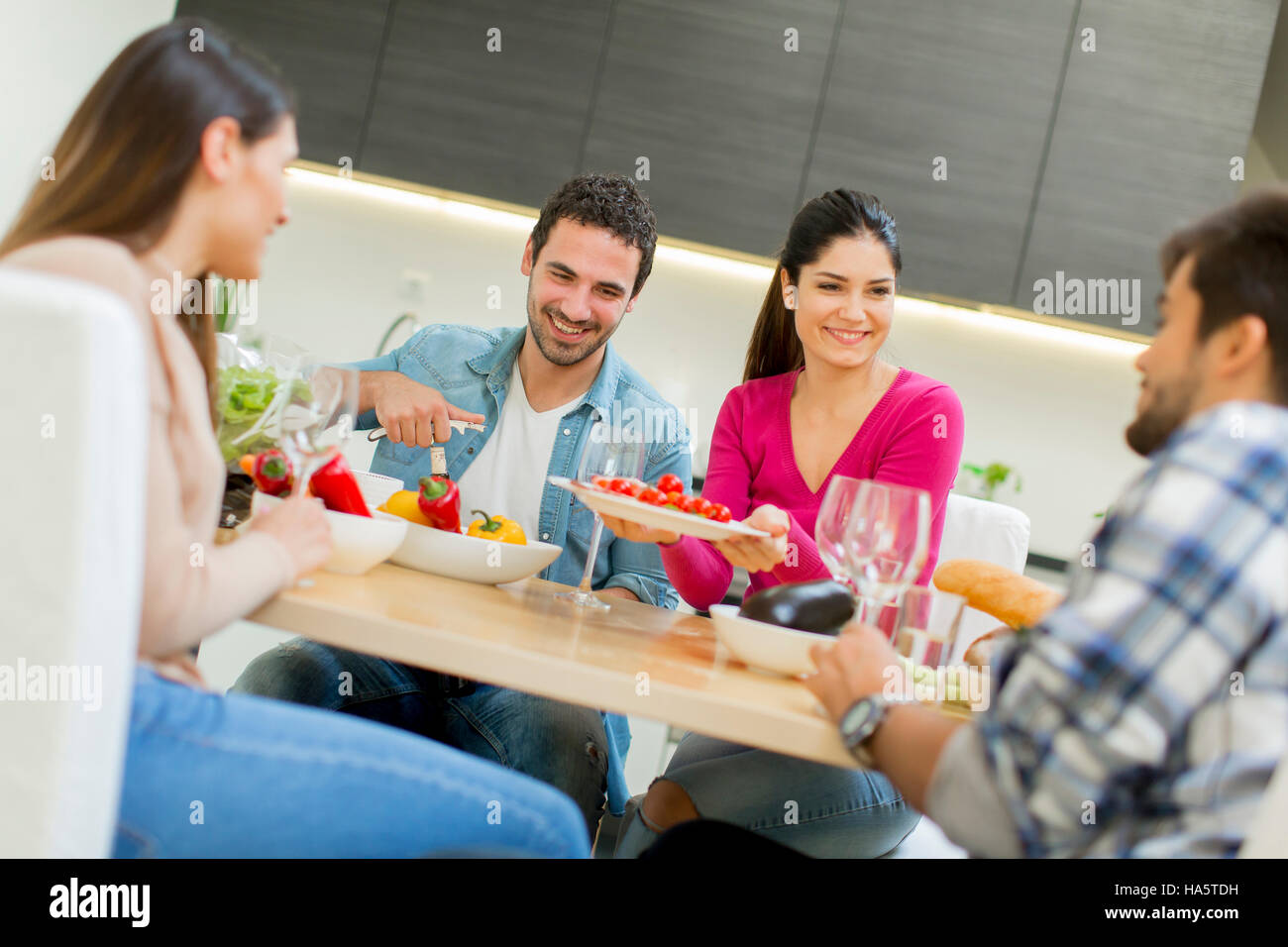 Group of happy young people sitting by the table eating and drinking red wine Stock Photo Alamy