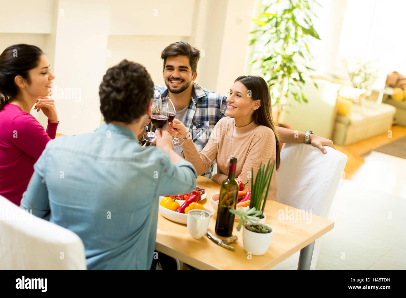 Group of happy young people sitting by the table eating and drinking red wine Stock Photo Alamy