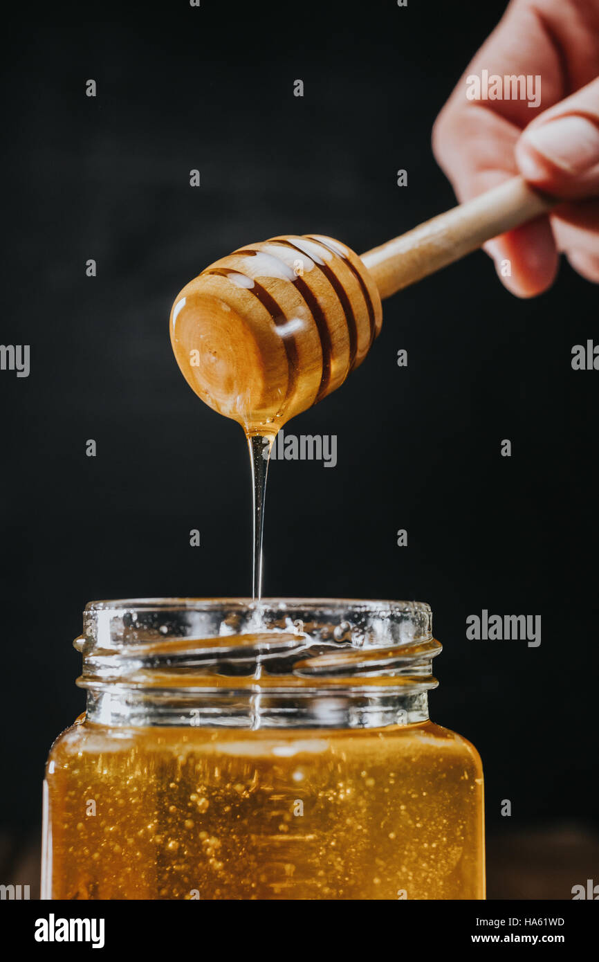 Person dipping honey stick in Stock Photo Alamy