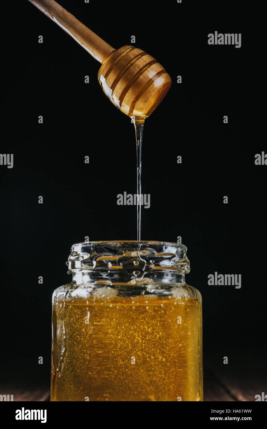 Person dipping honey stick in Stock Photo Alamy