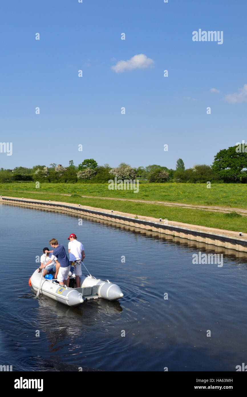 Three male teenagers having fun in a rubber dingy on the Trent & Mersey Canal near Alrewas. Stock Photo