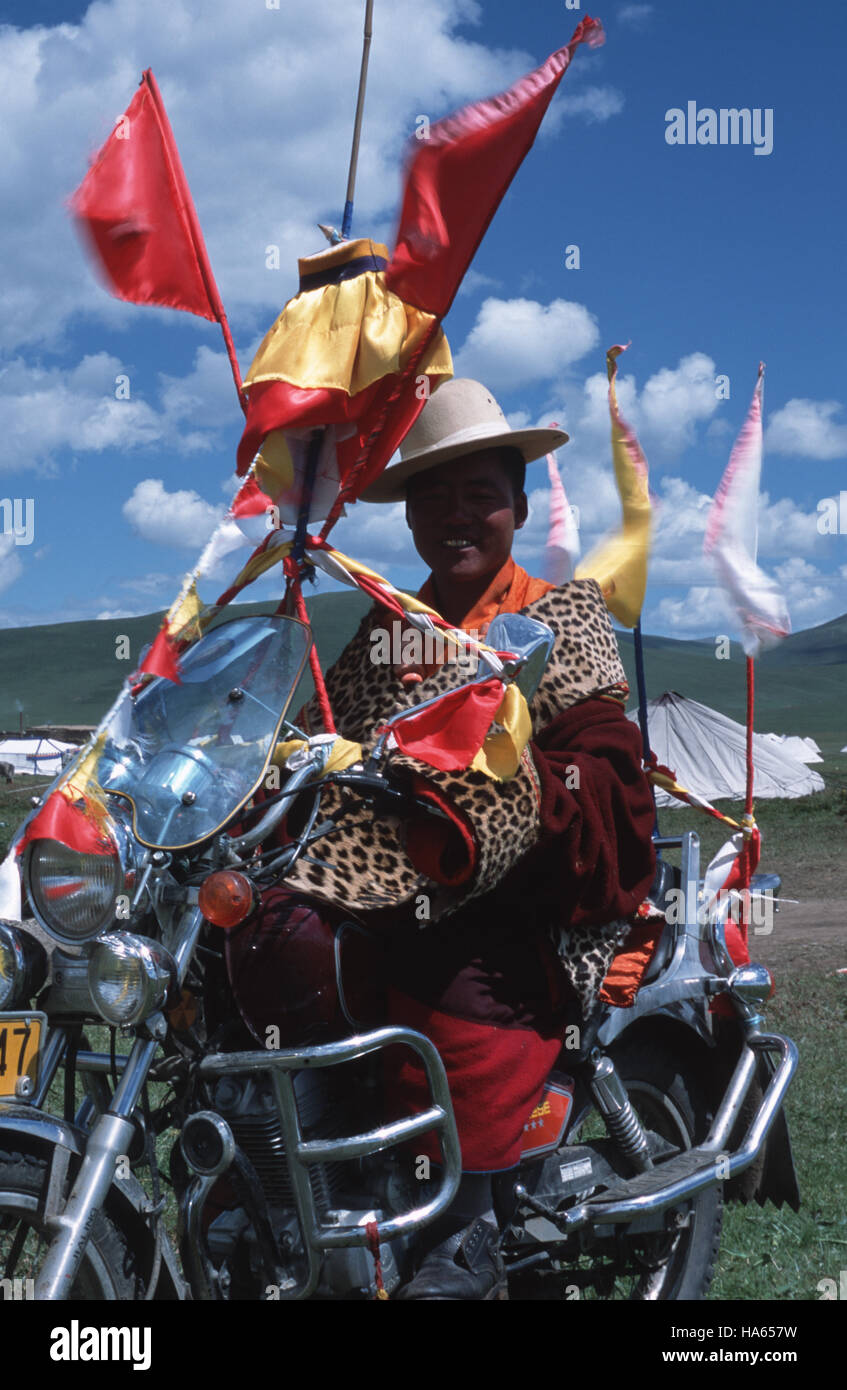 Caption: Ser'xu, Sichuan, China - Aug 2002. A wealthy monk and his motorbike at the Ser'xu Horseracing Festival.  Many temples are paid by the Chinese Stock Photo