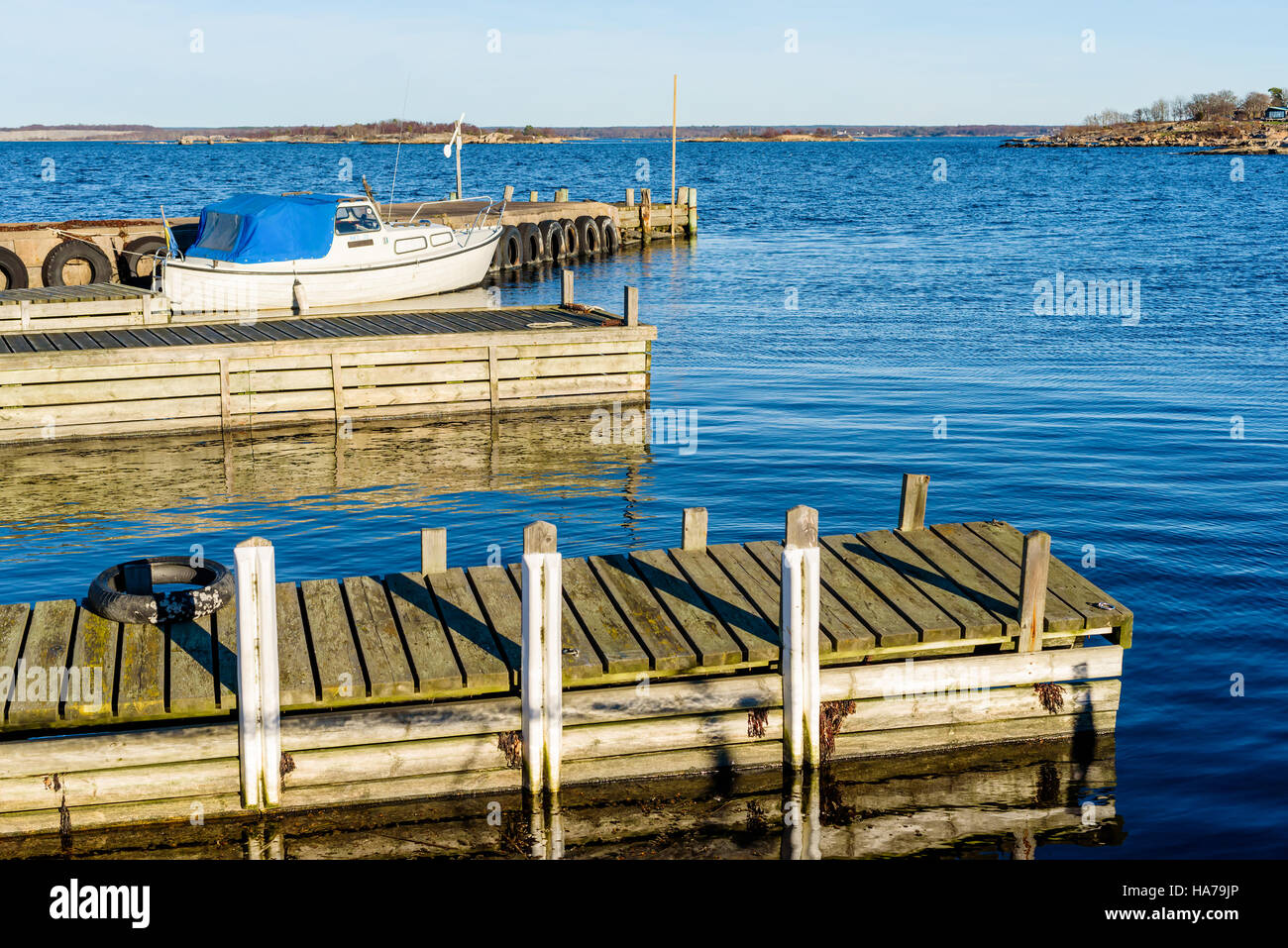 Tjurko, Sweden - November 24, 2016: Travel documentary of small local marina in fall. One motorboat moored dockside and the archipelago visible in the Stock Photo