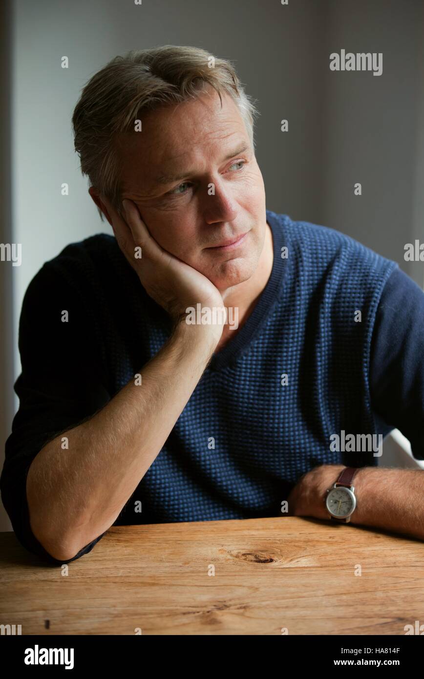 Man leaning on hand at table and contemplate Stock Photo