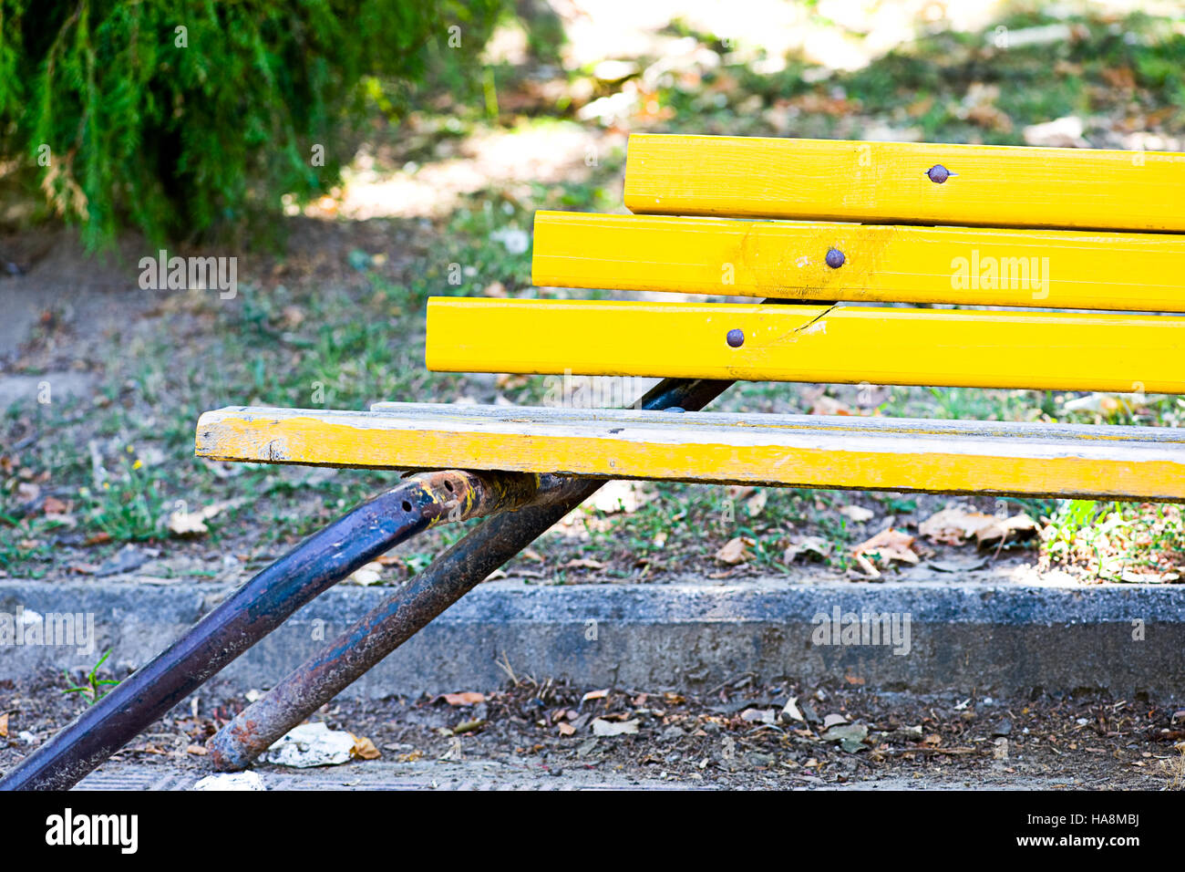 A bright yellow bench leaning over to the side in Greece Stock Photo