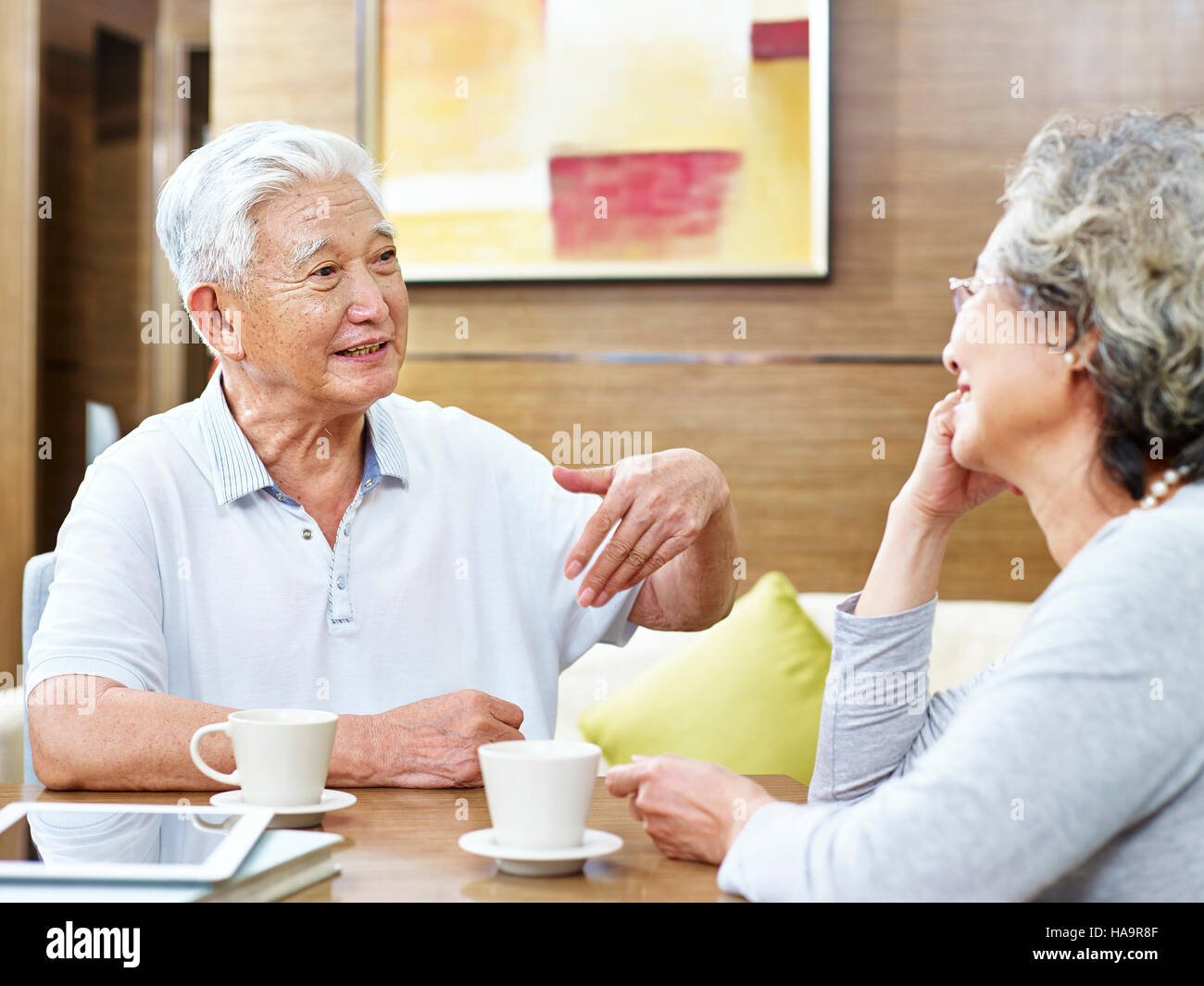 loving senior asian couple sitting at table having coffee and a heated discussion. Stock Photo