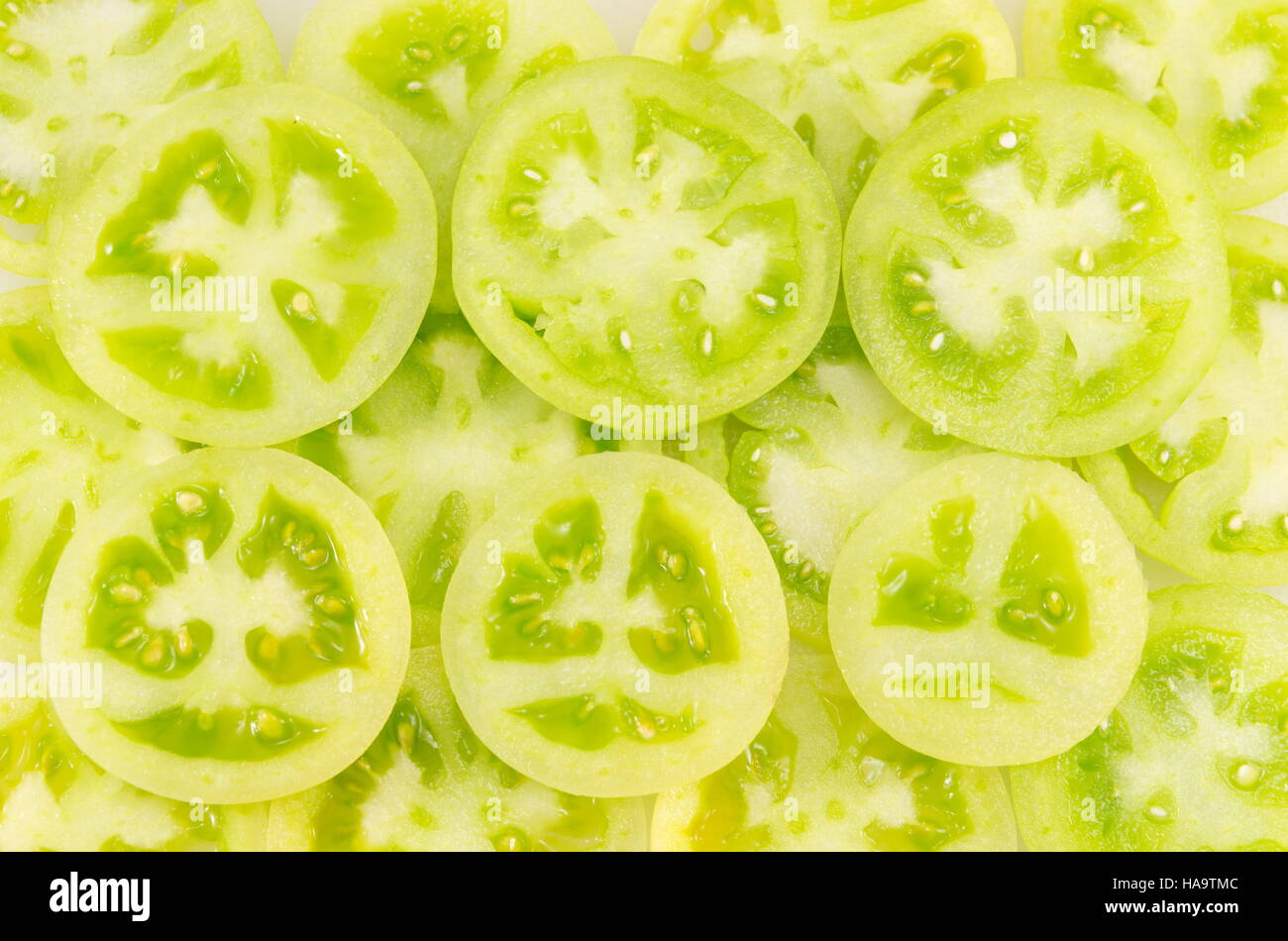 green tomatoes sliced into circles and arranged together next to a red tomato slice Stock Photo