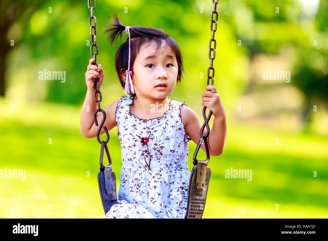 Adorable girl enjoys play time on the swing. Stock Photo