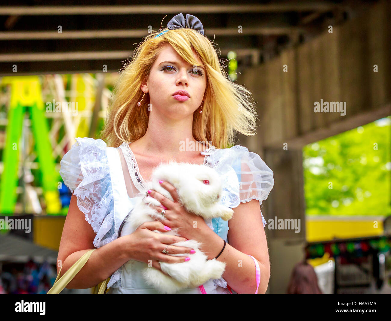 Attractive female model in Alice costume, with white rabbit, in wonderland. Stock Photo