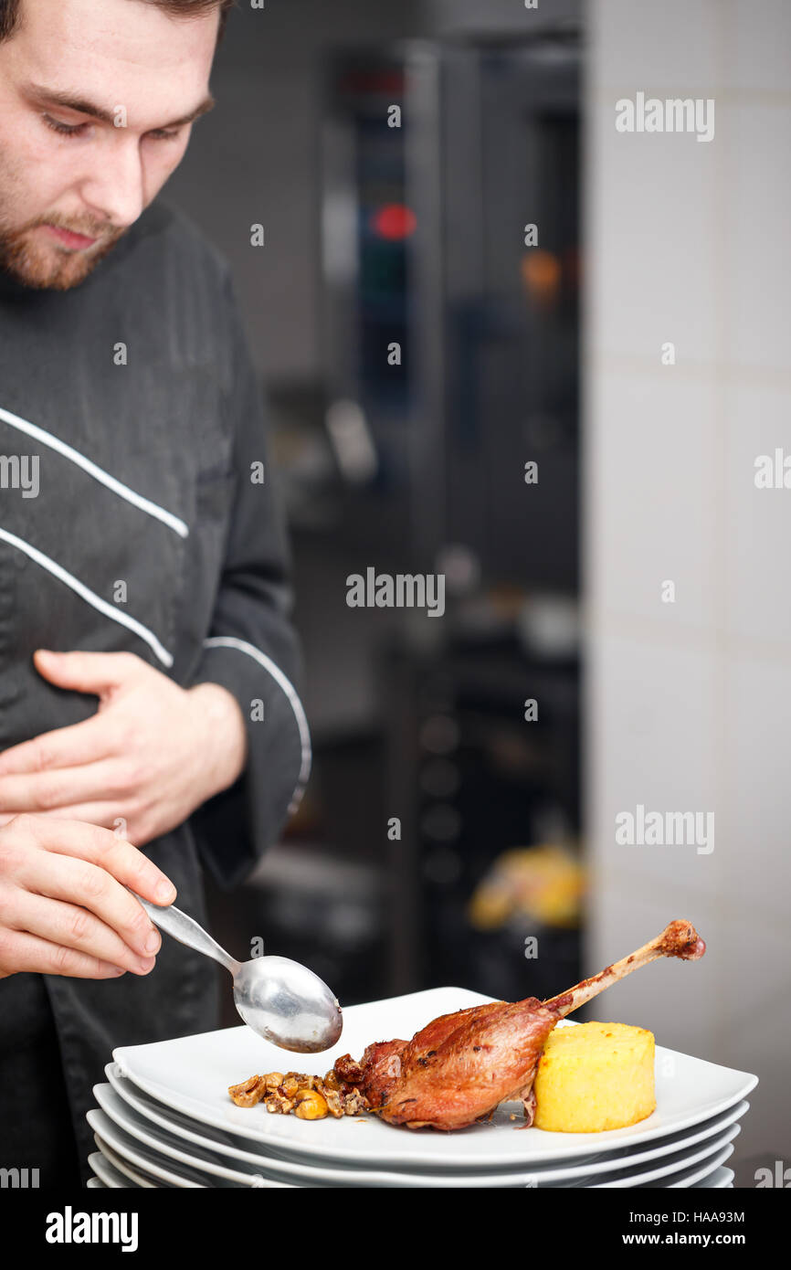Young Male Cook Chef In Black Uniform Decorating Food On The Plate