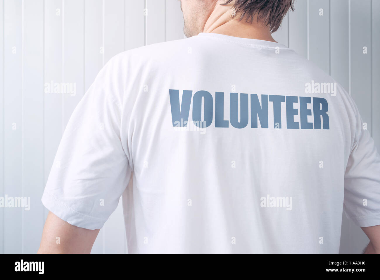 Guy wearing shirt with Volunteer label printed on back, confident friendly person offering help Stock Photo