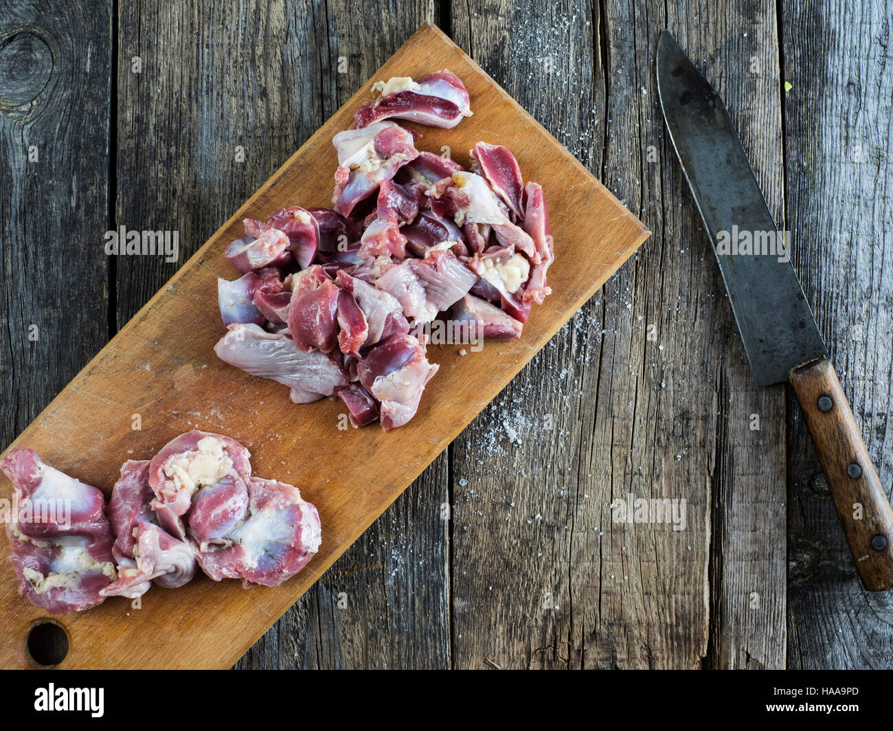 https://c8.alamy.com/comp/HAA9PD/raw-chicken-gizzards-on-cutting-board-on-weathered-old-wooden-table-HAA9PD.jpg