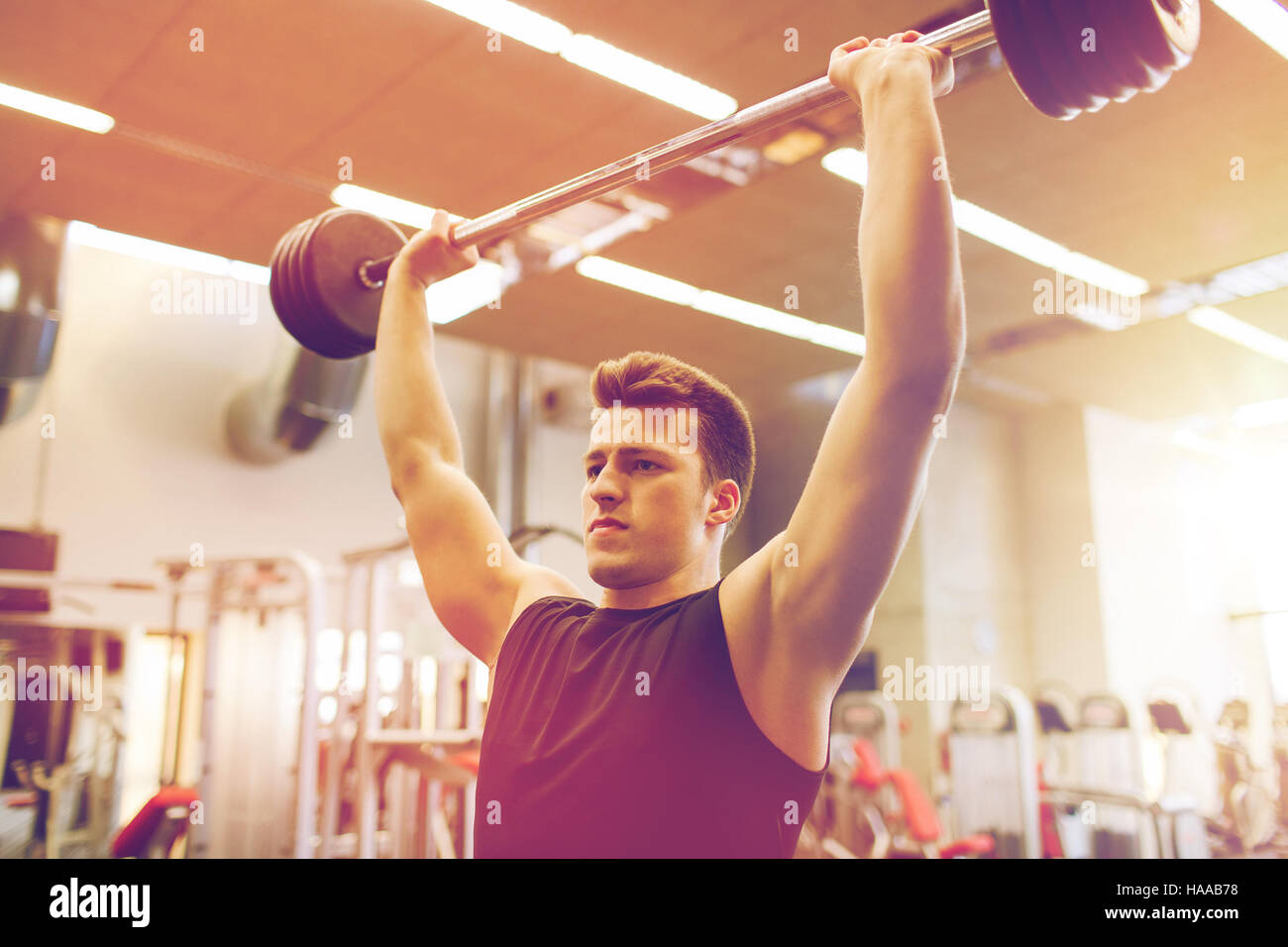 young man flexing muscles with barbell in gym Stock Photo Alamy