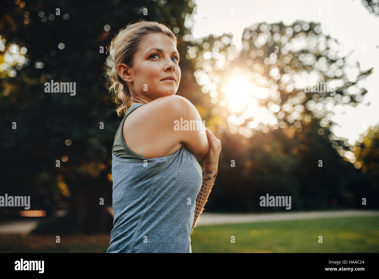 Portrait of beautiful young woman exercising in the park. Caucasian female fitness model working out in the morning. Stock Photo