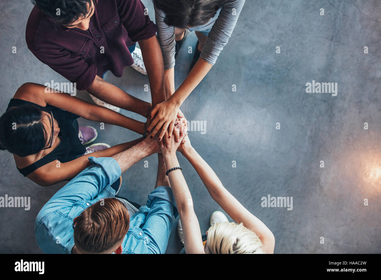 Top view of young people putting their hands on top of each other. Young students making a stack of hands with copy space. Stock Photo