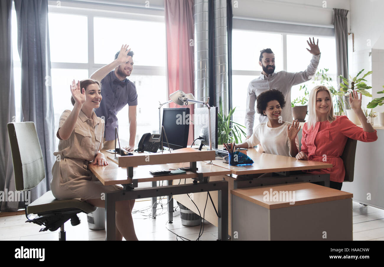 happy creative team waving hands in office Stock Photo - Alamy