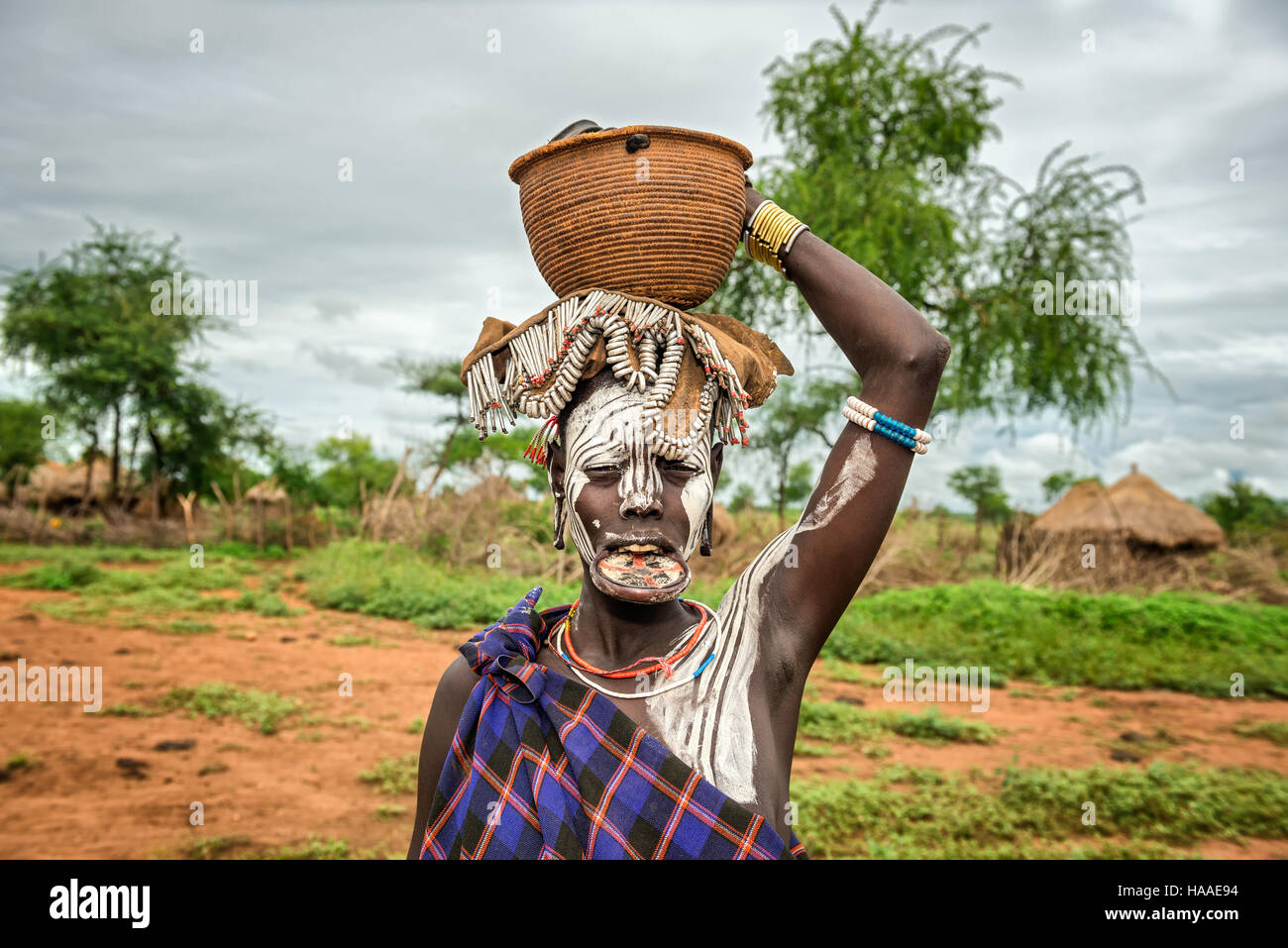 Woman from the african tribe Mursi with big lip plate and with a basket on her head Stock Photo