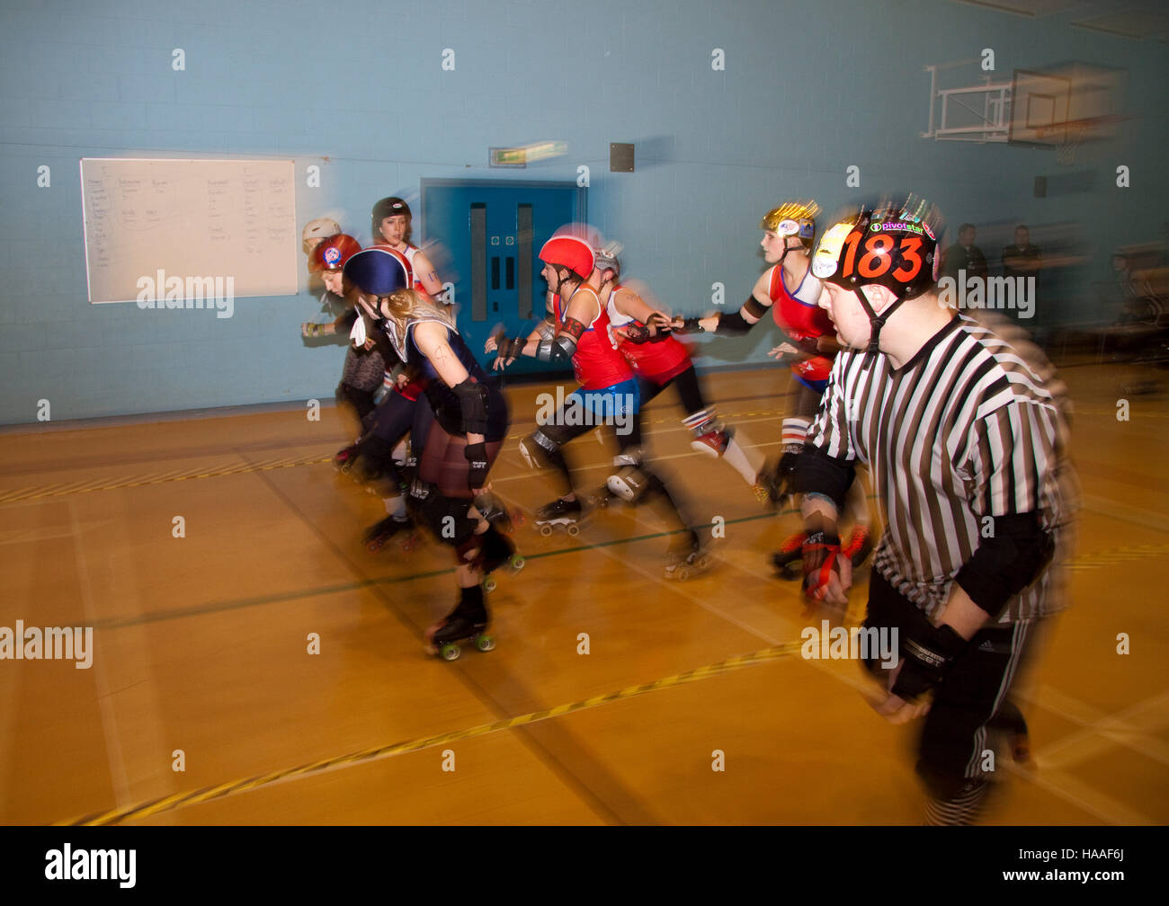 A roller derby jam in progress with a jammer ref in the foreground