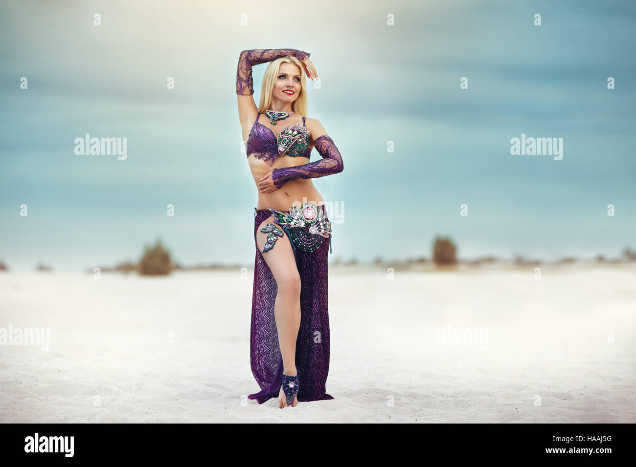 Beautidul smiling lady dancing Belly dance in the sands desert Stock Photo