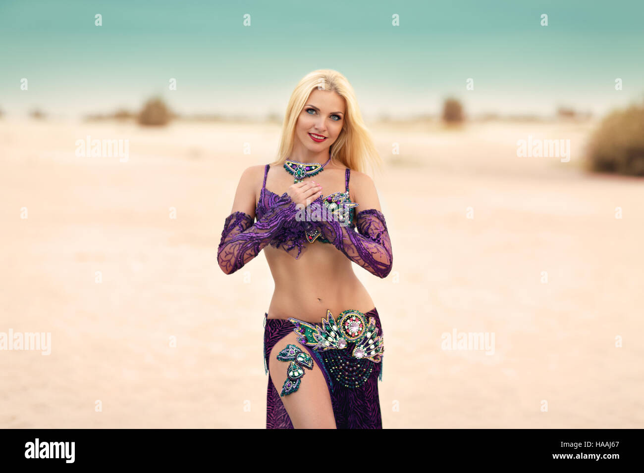 Beautidul smiling lady dancing Belly dance in the sands desert Stock Photo