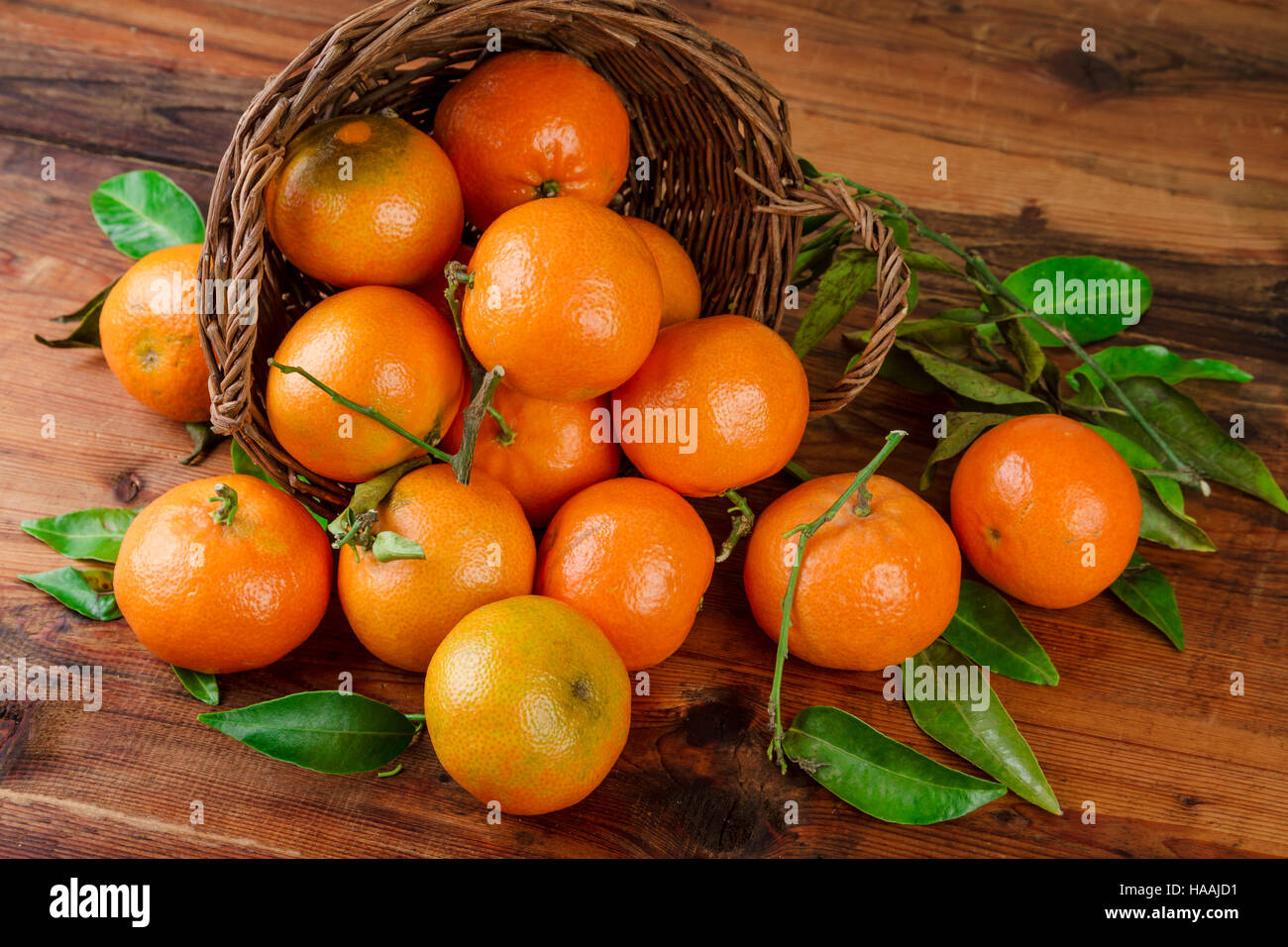 Tangerines basket scattered fruits on woden table Stock Photo