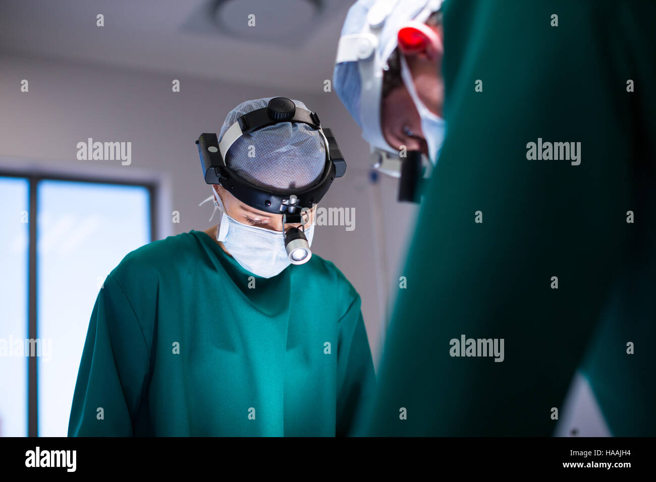 Surgeons wearing surgical loupes while performing operation Stock Photo