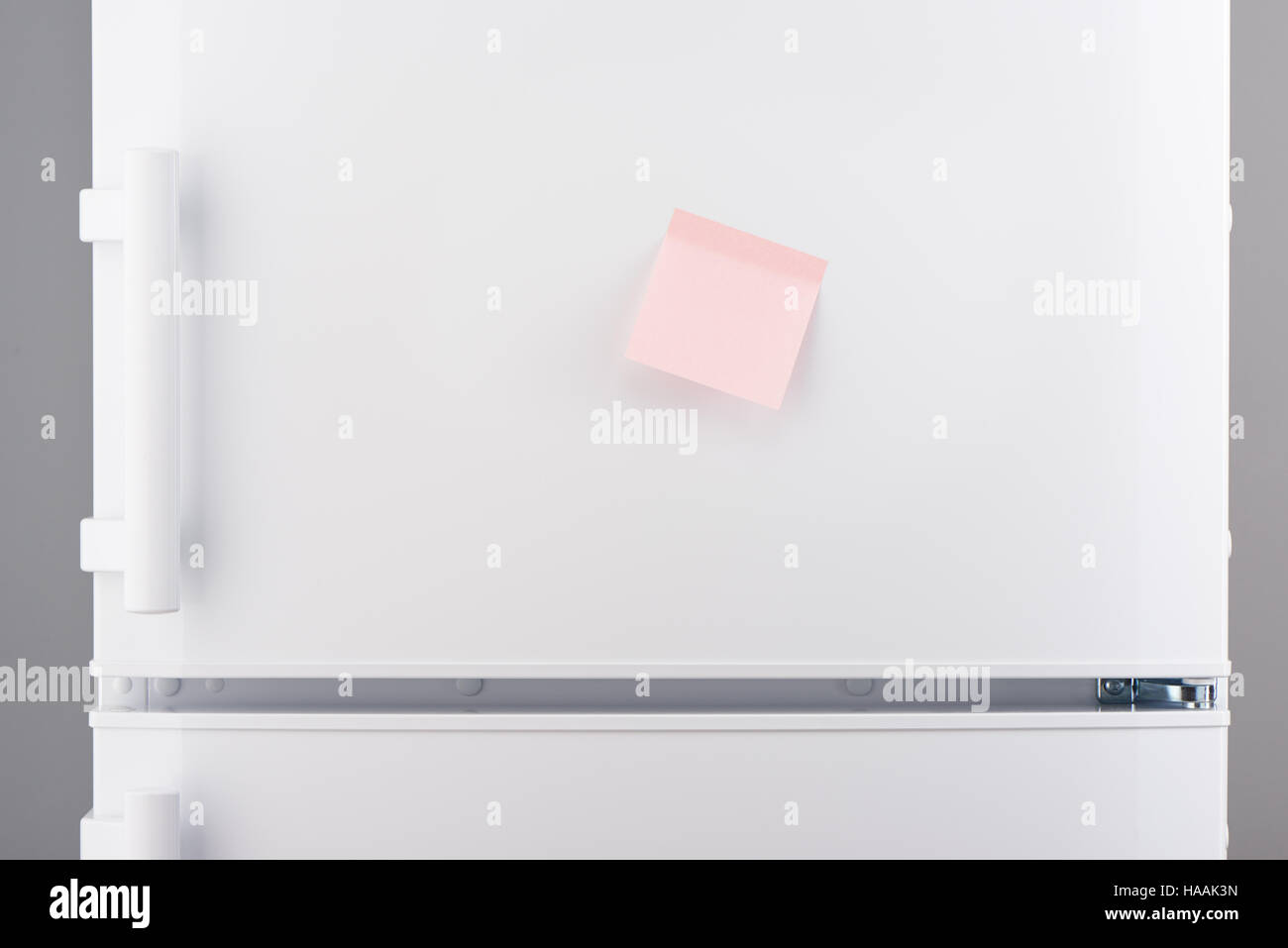 Blank light pink sticky paper note on white refrigerator door Stock Photo