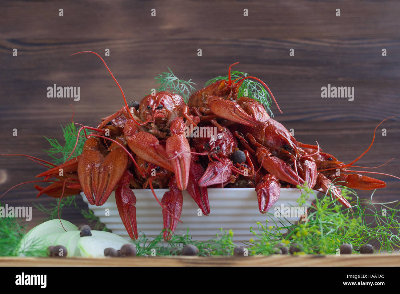 Plate of red boiled crayfishes with claws and fennel, onions and peppers on wooden background Stock Photo