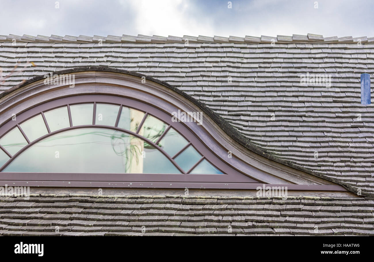 detail of an old eye brow window in a shingled roof Stock Photo