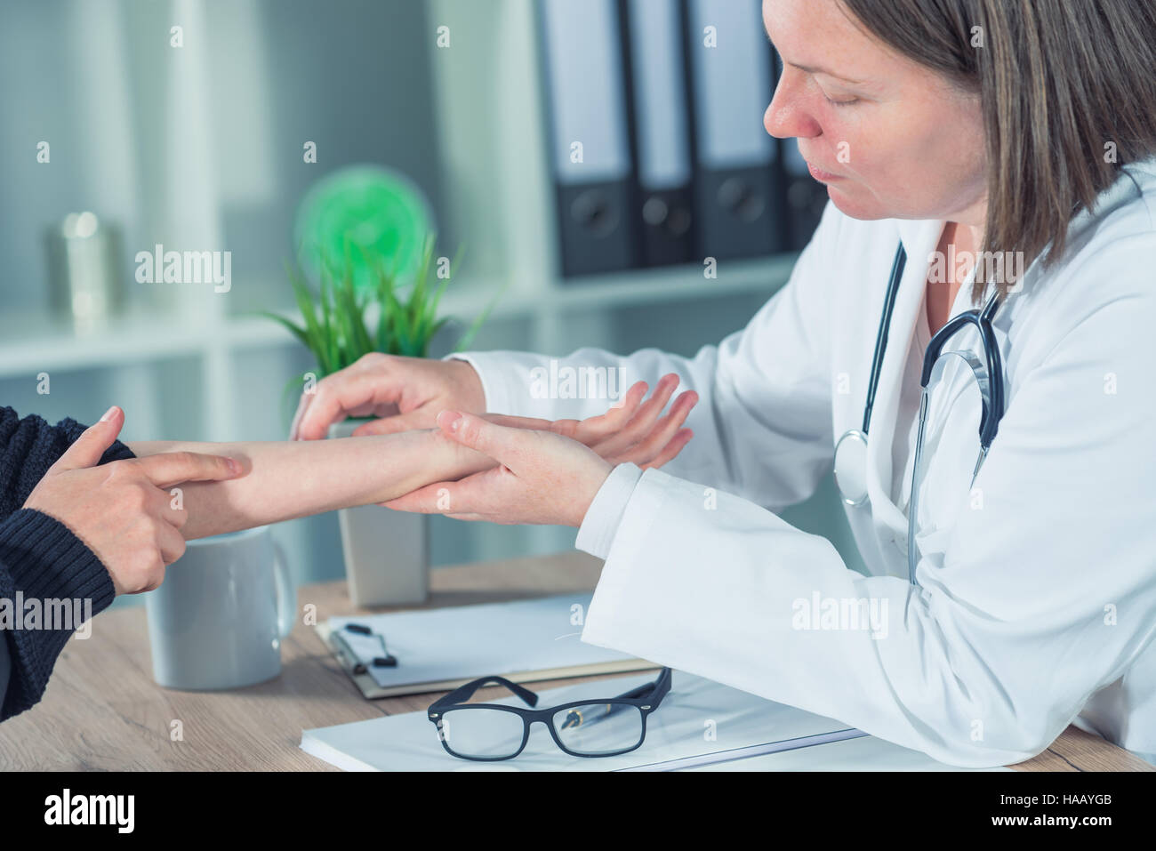 Female patient at orthopedic medical exam in doctor's hospital office, traumatology and medical consultation for hand wrist injury Stock Photo