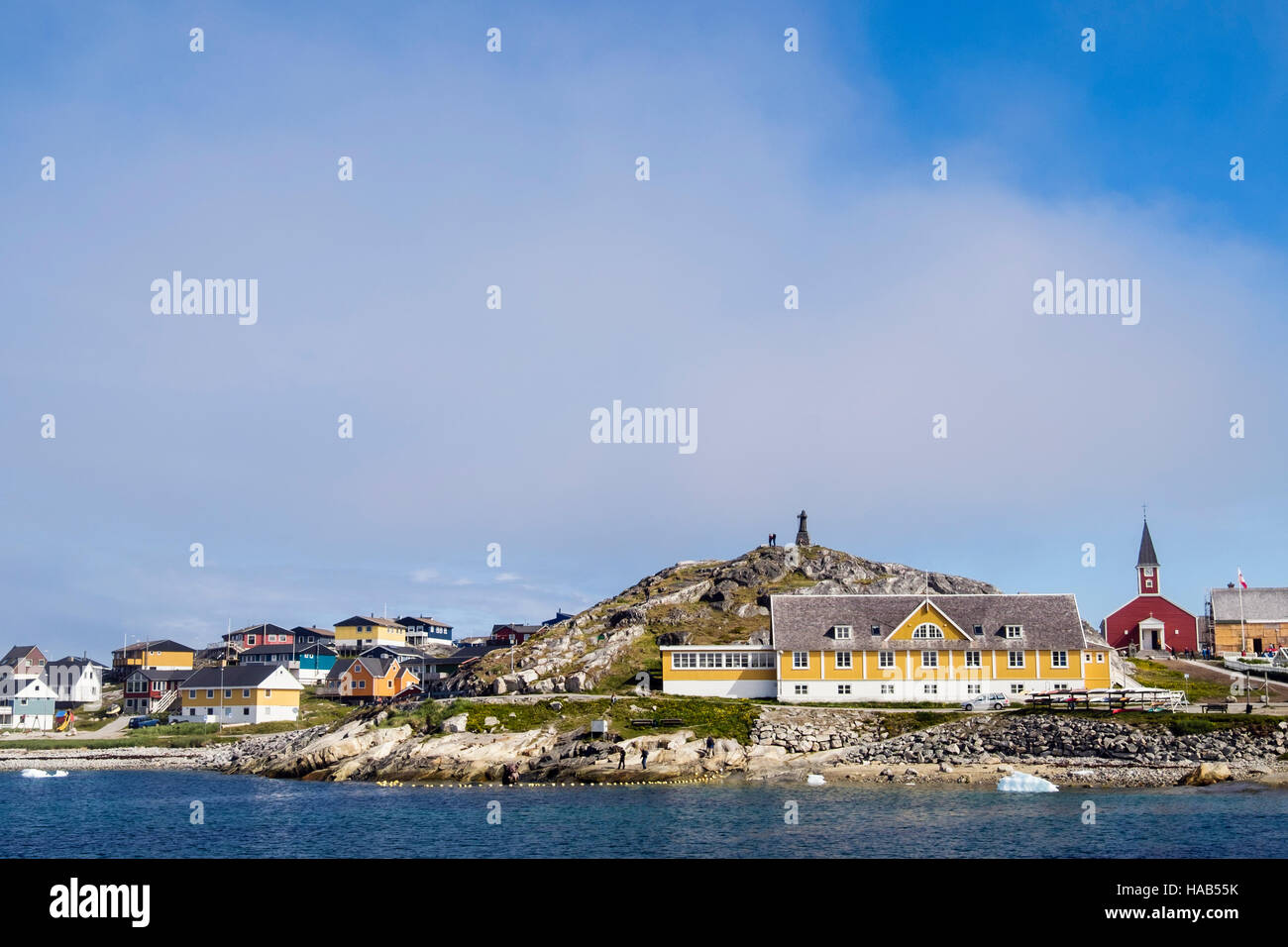 View across Colonial Harbour (Kolonihavnen) to old hospital and Hans Egede statue on a hilltop beside cathedral in summer 2016. Nuuk Greenland Stock Photo