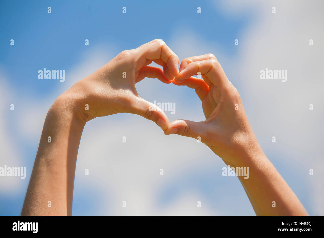 Symbol of love, human hands in heart shape towards blue sky Stock Photo ...