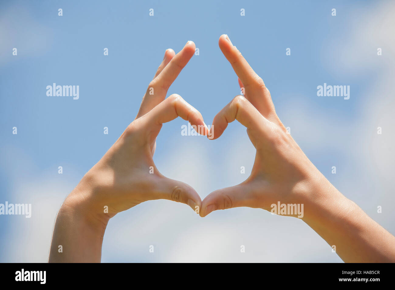 Symbol of love, human hands in heart shape towards blue sky Stock Photo ...