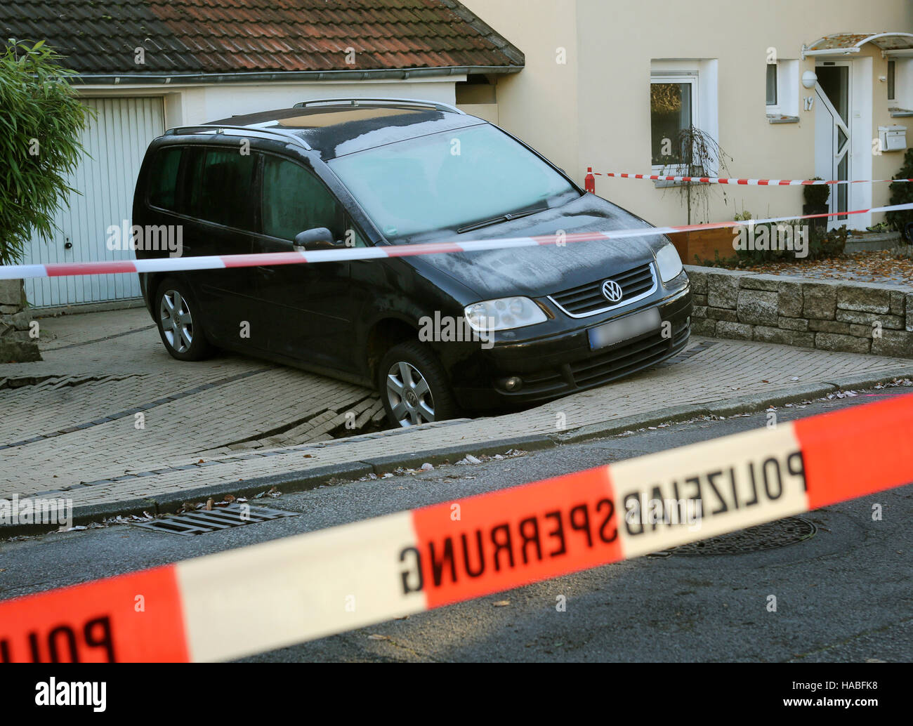 Essen, Germany. 29th Nov, 2016. A car in front of a residential property stuck in a large sinkhole in Essen, Germany, 29 November 2016. The hole, measuring three meters by seven and around 1.5 meters deep, emerged this afternoon. Photo: Roland Weihrauch/dpa/Alamy Live News Stock Photo